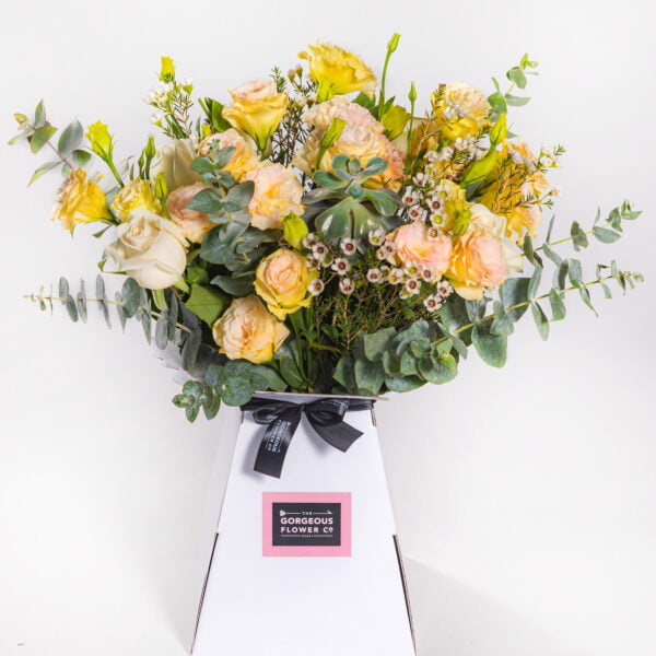 A combination of Apricot Lisianthus, Cream Roses, Wax flower with a succulent in a vase by The gorgeous flower co