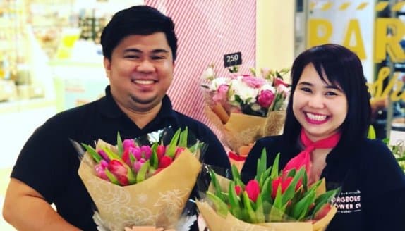 Two employees holding flowers and smiling